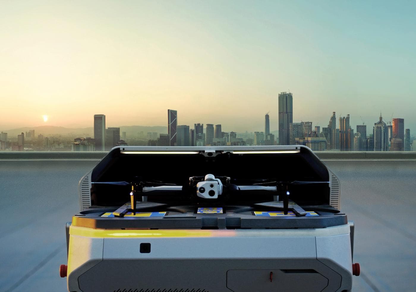 A Skydio X10 sitting in its open rooftop dock at sunrise, a city skyline behind it